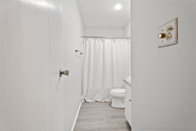 bathroom featuring a textured ceiling, toilet, a shower with curtain, and wood finished floors
