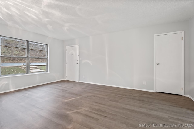 empty room with baseboards, wood finished floors, and a textured ceiling