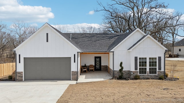 modern farmhouse with a garage, stone siding, board and batten siding, and concrete driveway