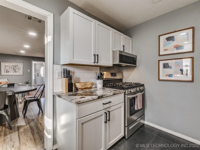 kitchen with tasteful backsplash, visible vents, light stone countertops, stainless steel appliances, and white cabinetry