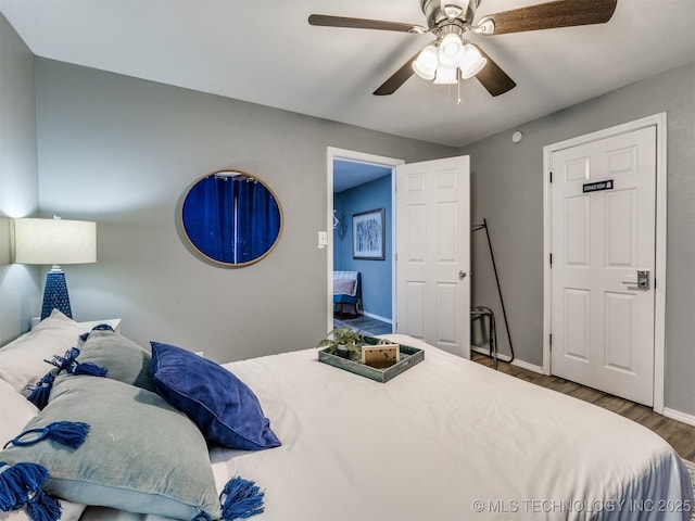 bedroom featuring ceiling fan, baseboards, and wood finished floors