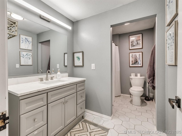 bathroom with toilet, visible vents, baseboards, vanity, and tile patterned floors