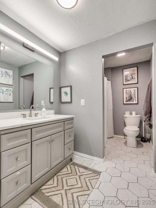 full bathroom featuring toilet, baseboards, a textured ceiling, and vanity