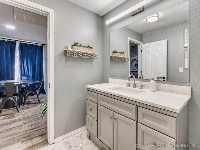 bathroom featuring a textured wall, vanity, and baseboards