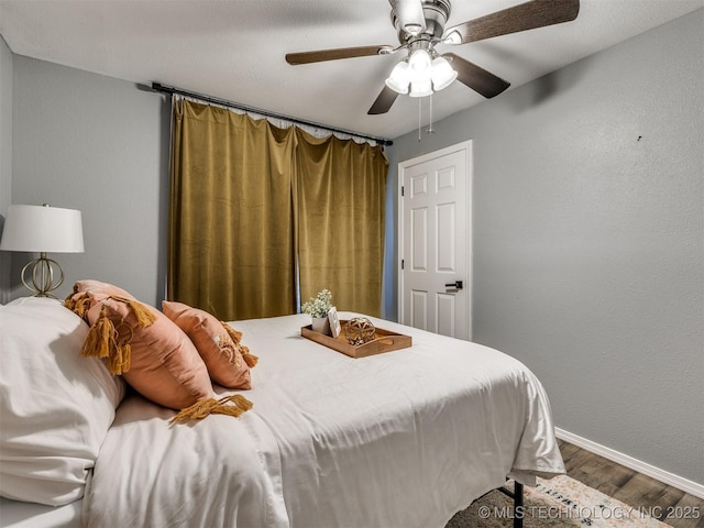 bedroom featuring a ceiling fan, baseboards, and wood finished floors