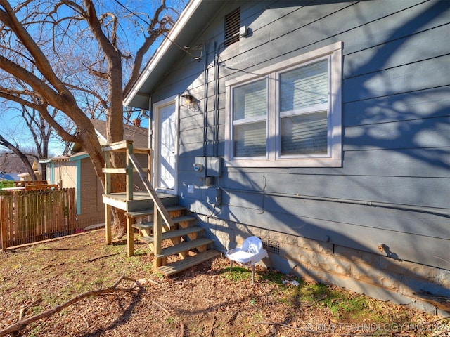 view of side of property with crawl space and fence