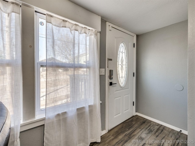 foyer featuring a textured ceiling, dark wood-style flooring, and baseboards