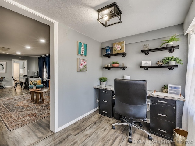 office area featuring a textured ceiling, light wood finished floors, visible vents, and baseboards