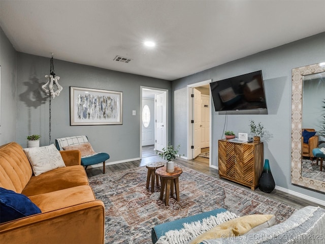 living room with baseboards, visible vents, and wood finished floors