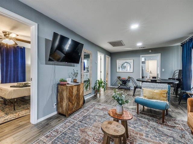 living room with visible vents, ceiling fan, baseboards, and wood finished floors