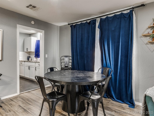 dining space featuring baseboards, visible vents, and light wood-style floors