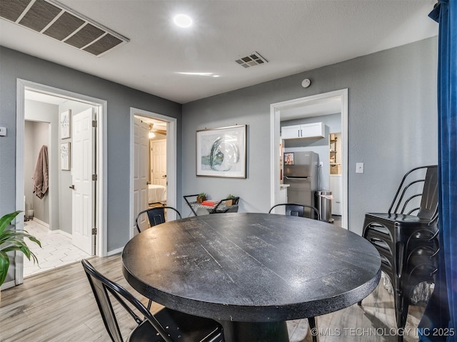 dining room with light wood-style flooring, visible vents, and baseboards