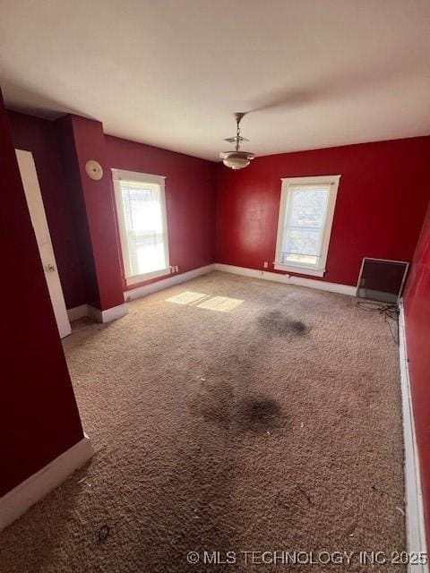 unfurnished room featuring carpet and baseboards