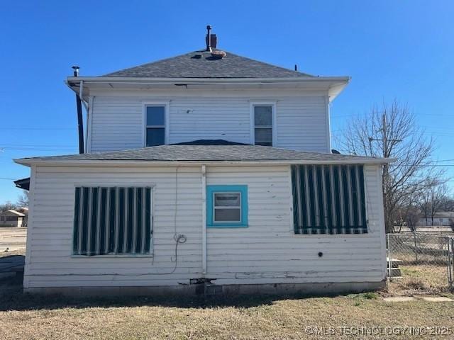 back of house with a shingled roof, crawl space, and fence