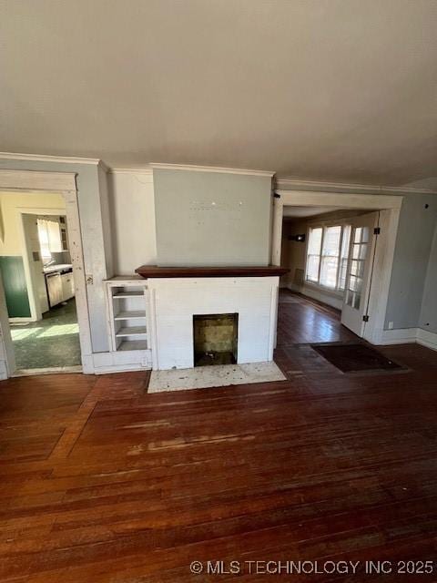 unfurnished living room featuring a fireplace with flush hearth, baseboards, wood finished floors, and crown molding