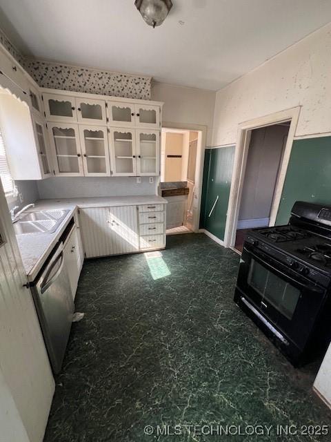 kitchen featuring black gas range, white cabinetry, glass insert cabinets, and a sink