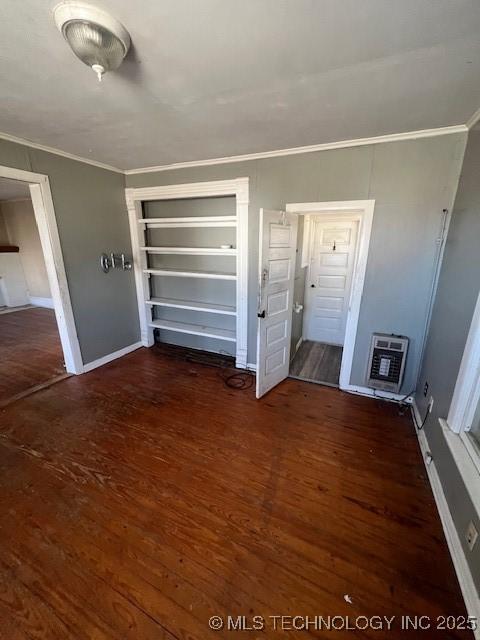 interior space with crown molding, baseboards, wood finished floors, and heating unit