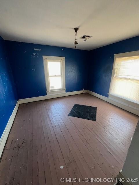 spare room with hardwood / wood-style flooring, baseboards, and visible vents