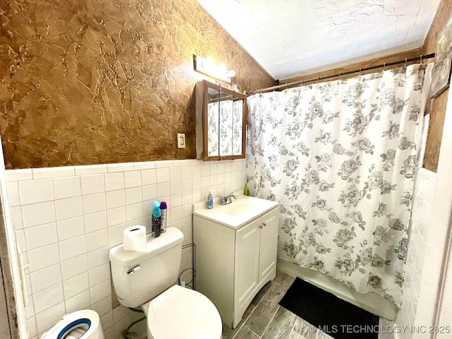 bathroom with toilet, a shower with curtain, a wainscoted wall, and vanity