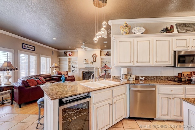 kitchen featuring beverage cooler, a sink, open floor plan, appliances with stainless steel finishes, and crown molding