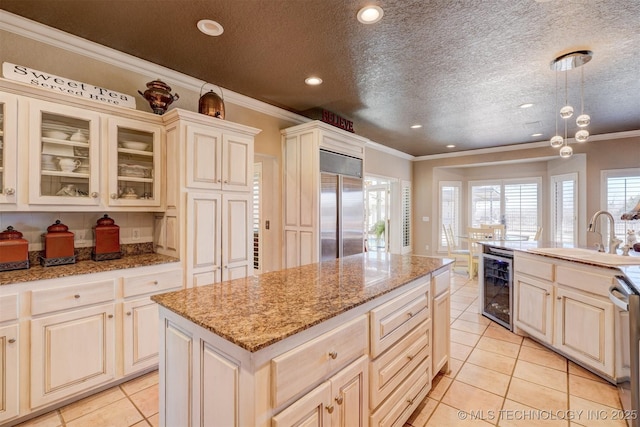 kitchen featuring built in fridge, beverage cooler, a sink, a center island, and crown molding