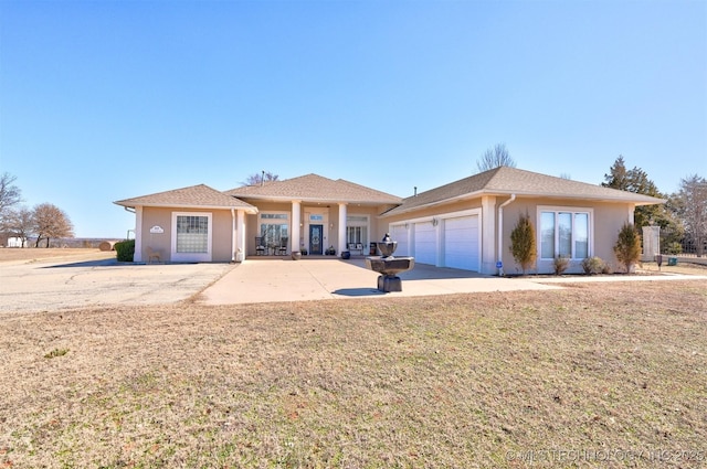 view of front of home with a garage, a front yard, and stucco siding