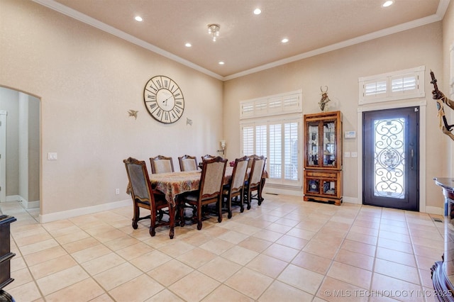 dining area featuring light tile patterned floors, baseboards, arched walkways, and crown molding