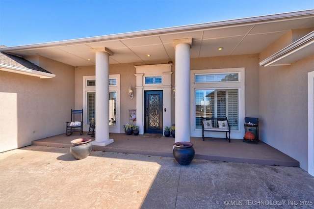 doorway to property with a porch and stucco siding