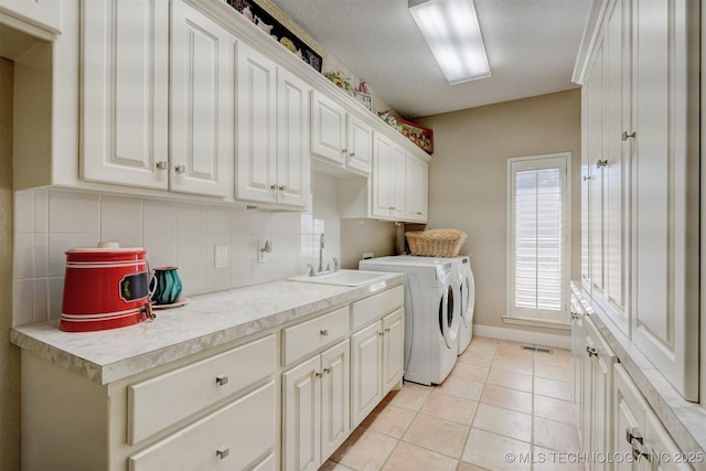 laundry area featuring cabinet space, visible vents, light tile patterned flooring, a sink, and separate washer and dryer