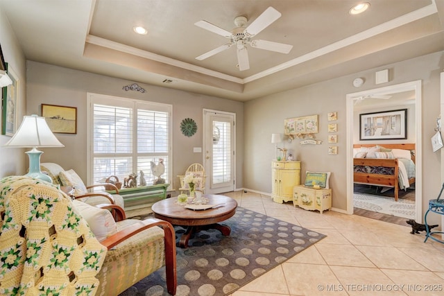 living area with a tray ceiling, crown molding, light tile patterned floors, ceiling fan, and baseboards