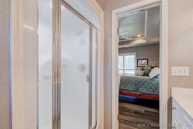 full bath with a stall shower, a raised ceiling, wood finished floors, ensuite bathroom, and vanity