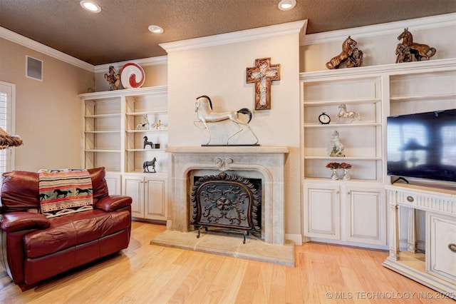 living room with visible vents, light wood-style flooring, ornamental molding, a high end fireplace, and a textured ceiling