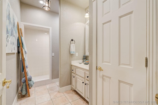 full bath featuring a walk in shower, tile patterned flooring, vanity, and baseboards