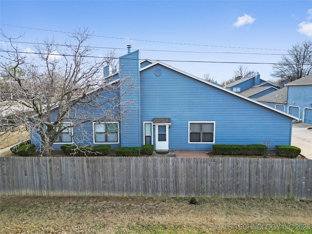 view of side of property with a chimney and fence