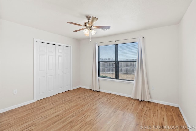 unfurnished bedroom featuring light wood-type flooring, a closet, ceiling fan, and baseboards