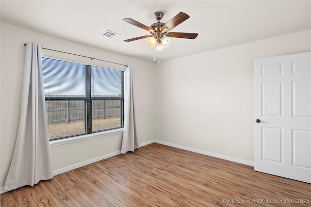 empty room featuring light wood-style floors, visible vents, baseboards, and a ceiling fan