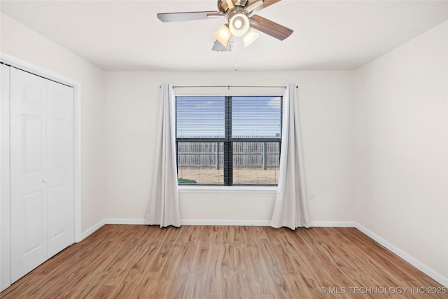 spare room with a ceiling fan, light wood-style flooring, and baseboards