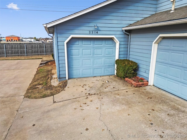 garage featuring fence and driveway