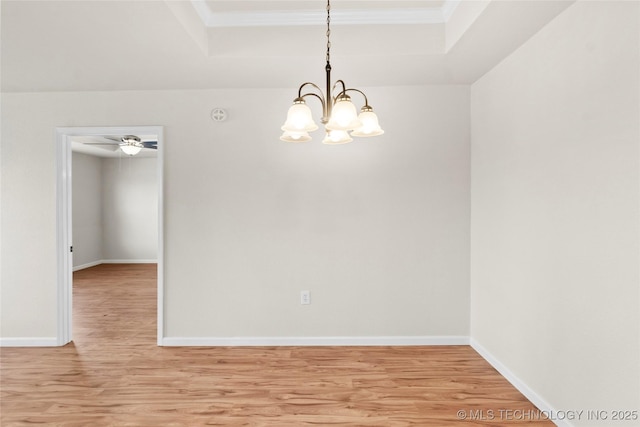 empty room featuring light wood-type flooring, a notable chandelier, crown molding, and baseboards