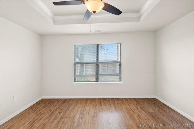 unfurnished room featuring ornamental molding, wood finished floors, a raised ceiling, and visible vents