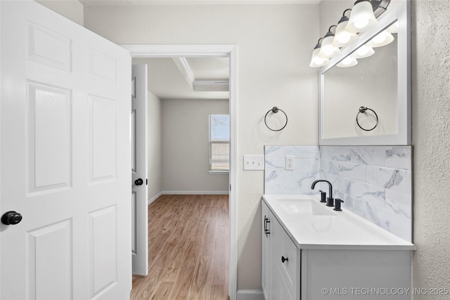 bathroom featuring a raised ceiling, a textured wall, vanity, and wood finished floors