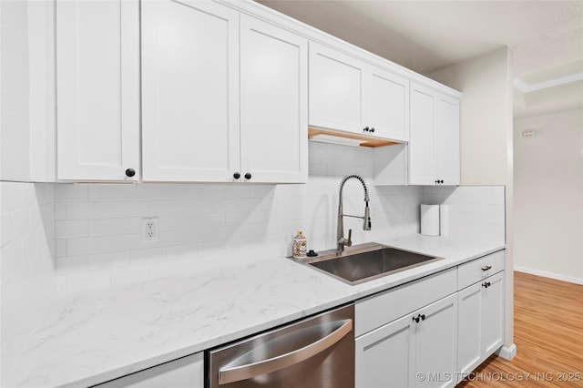 kitchen featuring a sink, white cabinetry, light wood-style floors, decorative backsplash, and dishwasher