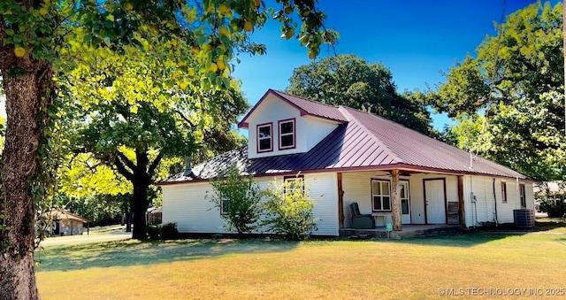 farmhouse-style home with ceiling fan, metal roof, cooling unit, a standing seam roof, and a front yard