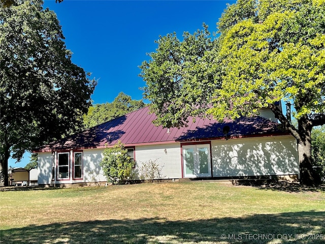 exterior space with metal roof, a front lawn, and a standing seam roof