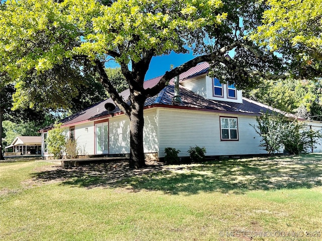 view of side of property featuring metal roof and a yard