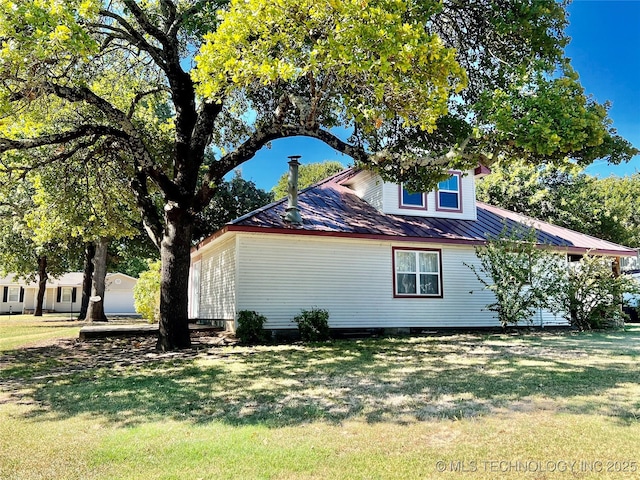 view of side of property with metal roof and a lawn