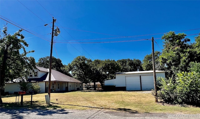 exterior space featuring a detached garage, a front lawn, and an outbuilding