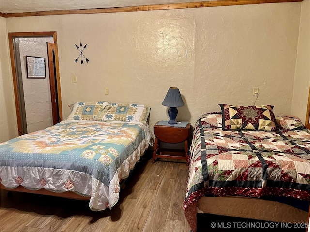 bedroom featuring hardwood / wood-style flooring and a textured wall