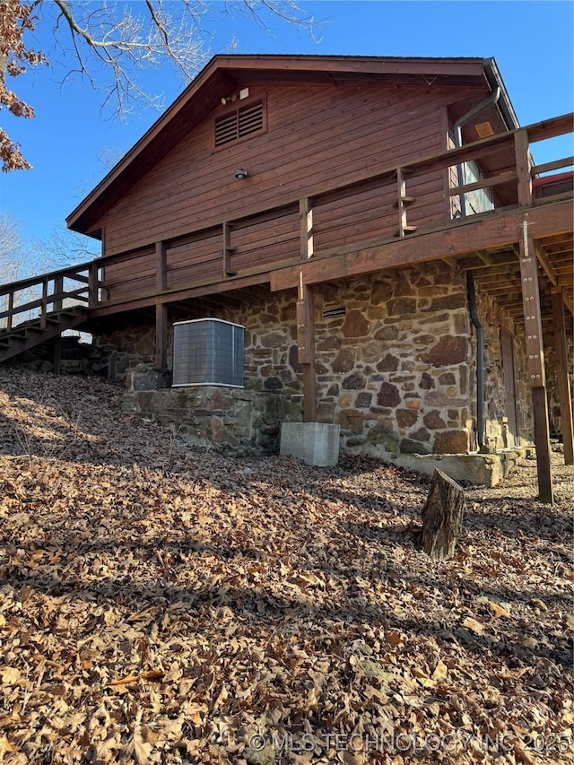 view of side of property featuring stone siding and a wooden deck