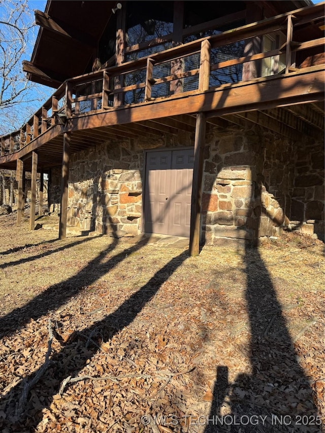 back of property featuring a deck and stone siding